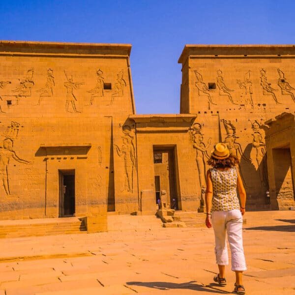 Turistas explorando el Templo de Philae en Asuán, con vistas al río.