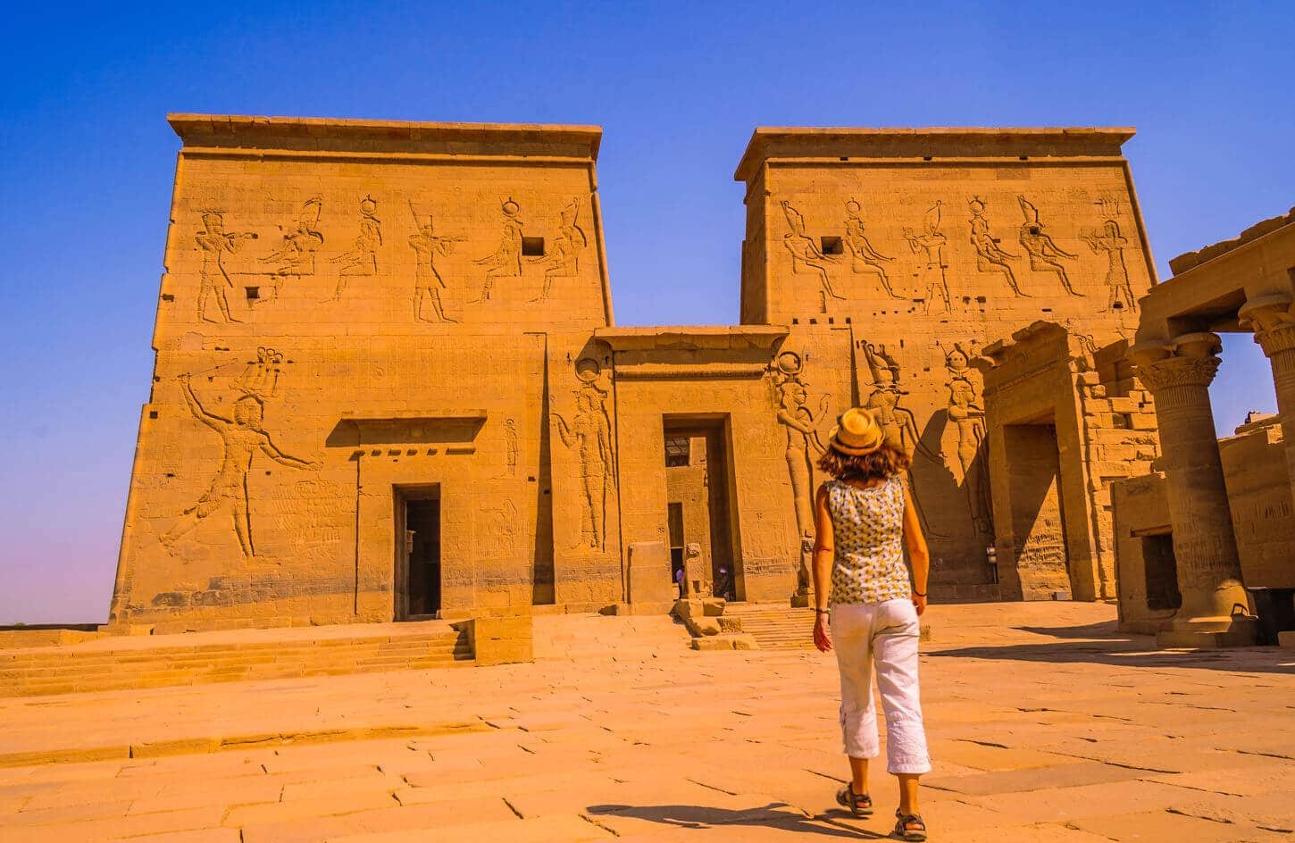Turistas explorando el Templo de Philae en Asuán, con vistas al río.