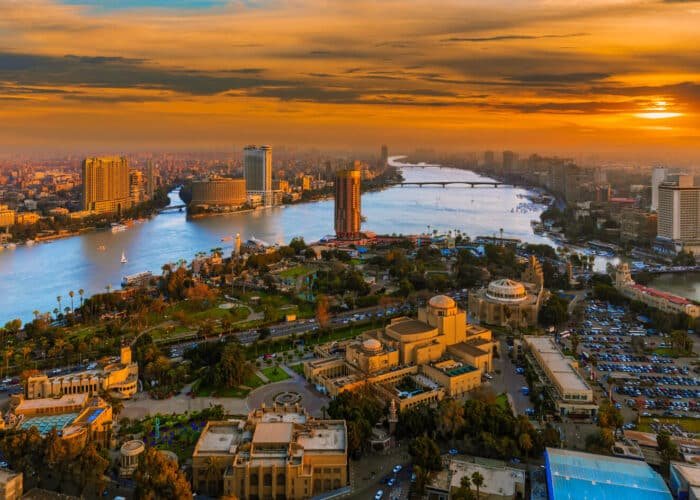 Vista aérea de El Cairo al atardecer con un cielo cálido y la silueta de la ciudad.
