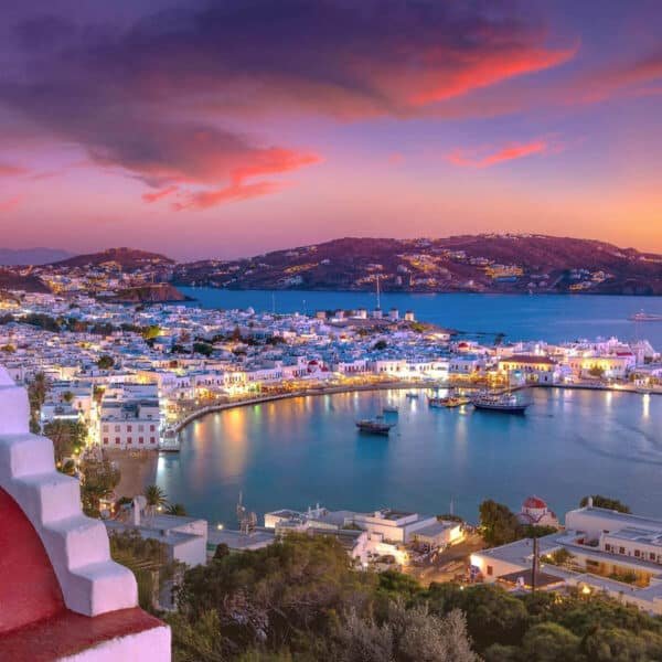 Vista nocturna de una ciudad griega iluminada con luces brillantes.