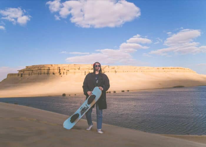 Niña practicando patinaje sobre arena en un entorno natural.