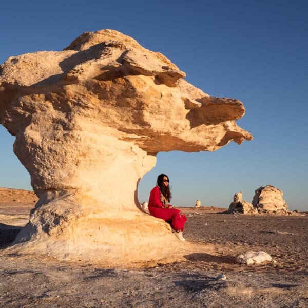 Chica de pie en las dunas blancas del Desierto Blanco bajo un cielo azul.