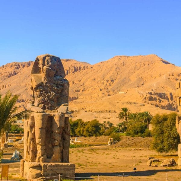 Estatuas colosales de Amenhotep III en Luxor, Egipto, destacando contra el cielo.