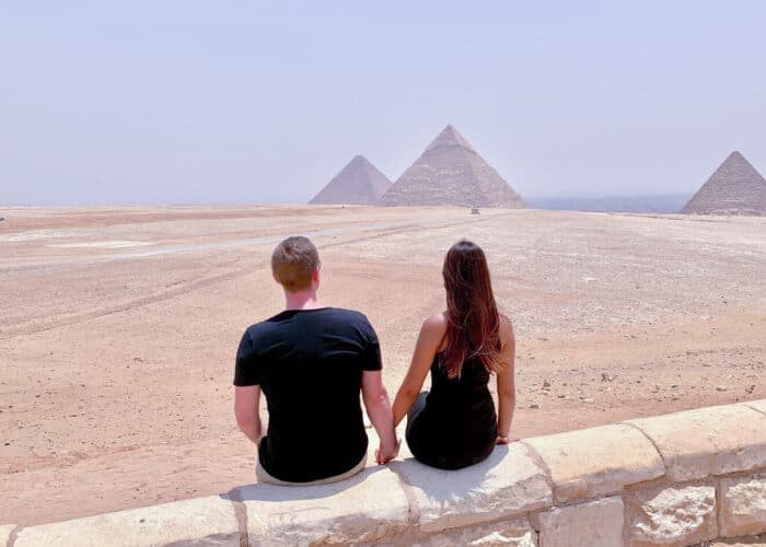 Pareja frente a las majestuosas pirámides de Giza en Egipto.