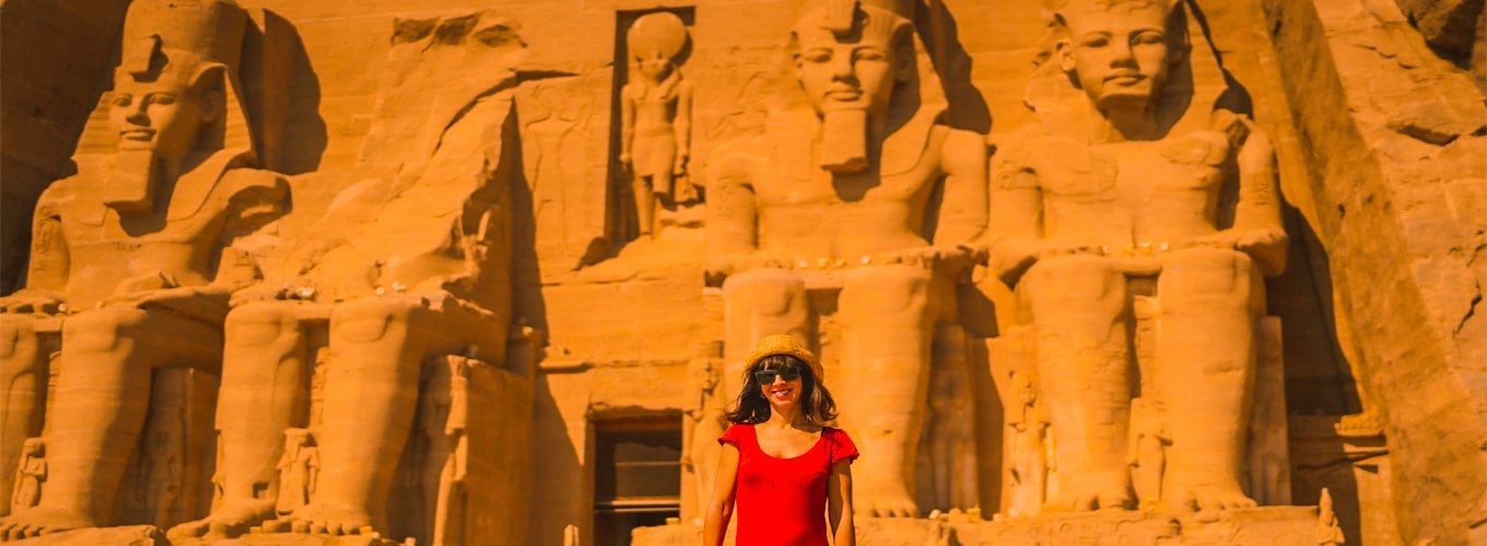 Turista joven con vestido rojo entrando al templo de Abu Simbel en Egipto.