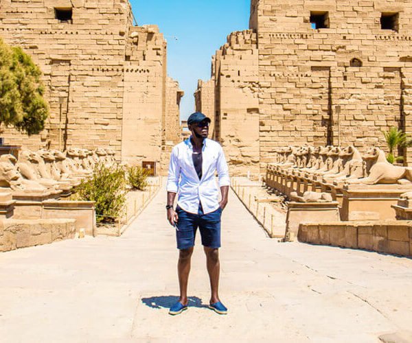 Hombre de pie en el Templo de Karnak, destacando la arquitectura antigua y majestuosa.