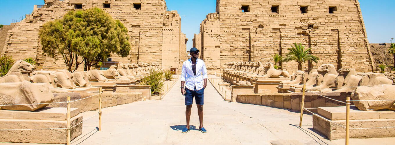Hombre de pie en el Templo de Karnak, destacando la arquitectura antigua y majestuosa.